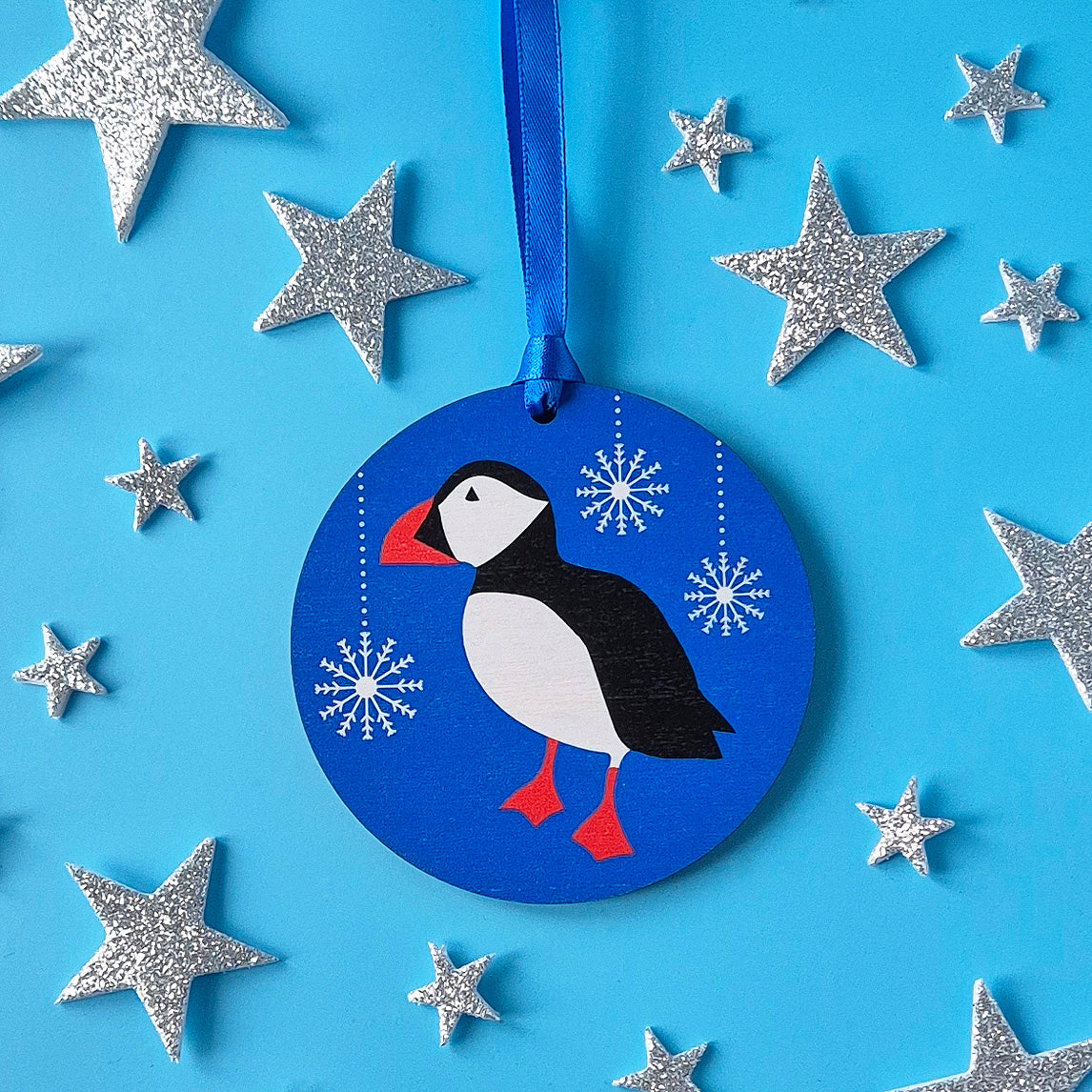 Blue with snowflakes wooden Puffin Christmas decoration surrounded by silver stars