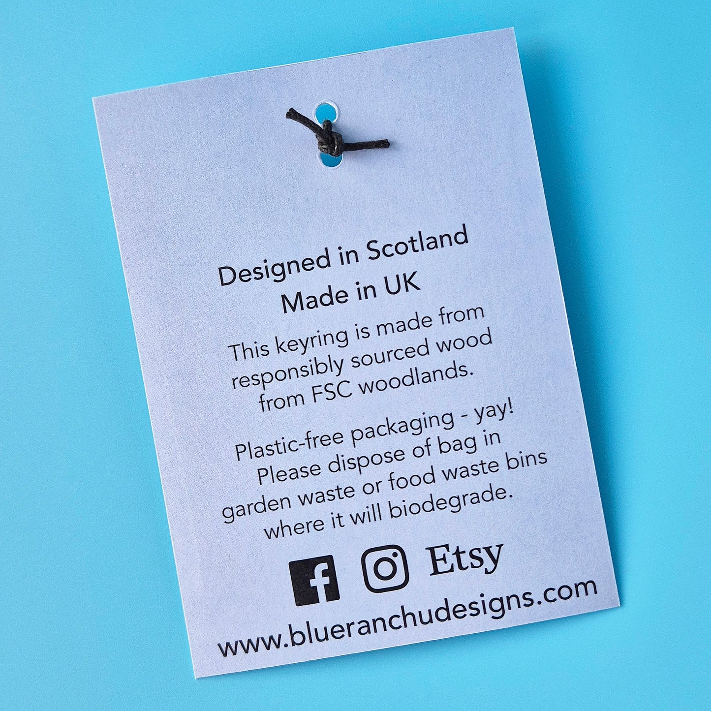 Keyring with a label on a blue background, featuring information about the product's origin and sustainability practices.
