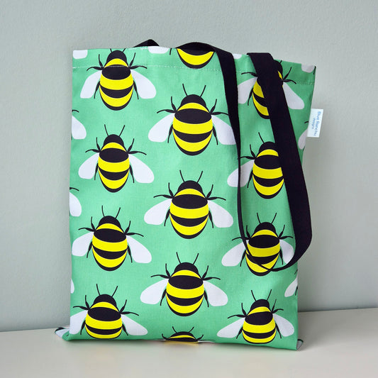 Cotton tote bag with repeating Bee design on a light green background