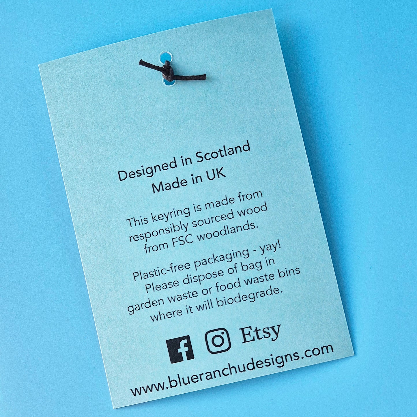 Product label on a blue background with text about the keyring's origin and sustainability practices.