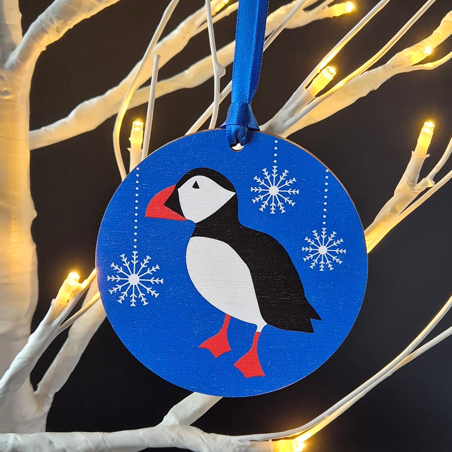Blue with snowflakes wooden Puffin Christmas decoration hanging from a Christmas tree