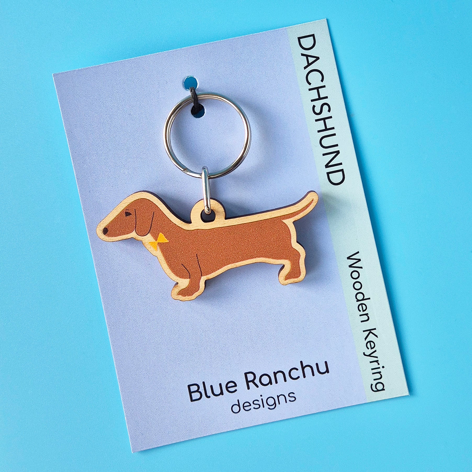 Red smooth haired Dachshund-shaped wooden keychain on a Blue Ranchu designs card with a blue background