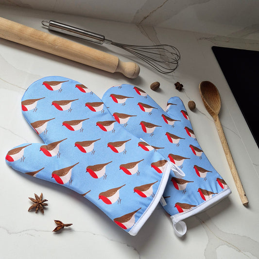 Oven mitts with Robin pattern on a kitchen counter with utensils.
