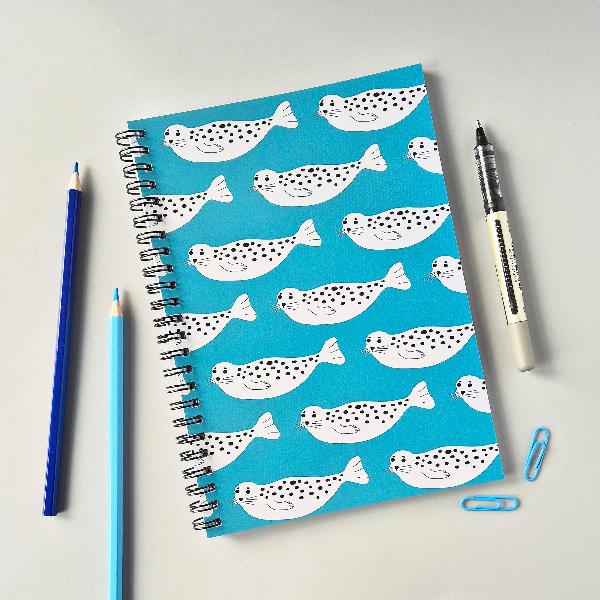 A5 wirebound notebook with a repeating Seal design on a turquoise background