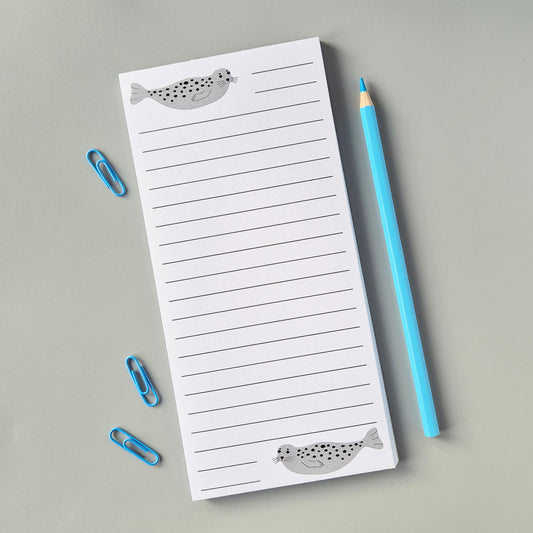 List pad with seal design, blue pencil, and paper clips on a gray background