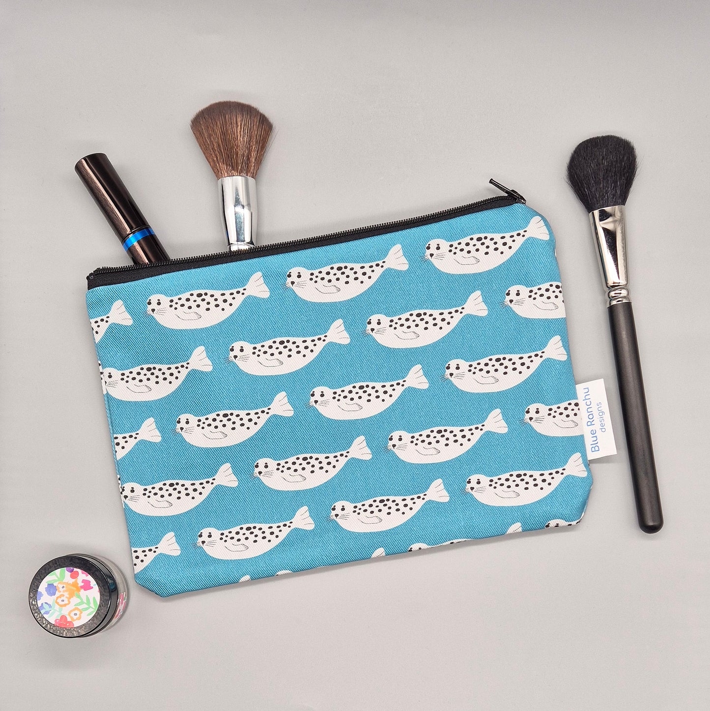 Grey Harbour Seal repeat pattern on a turquoise background handmade cosmetics bag