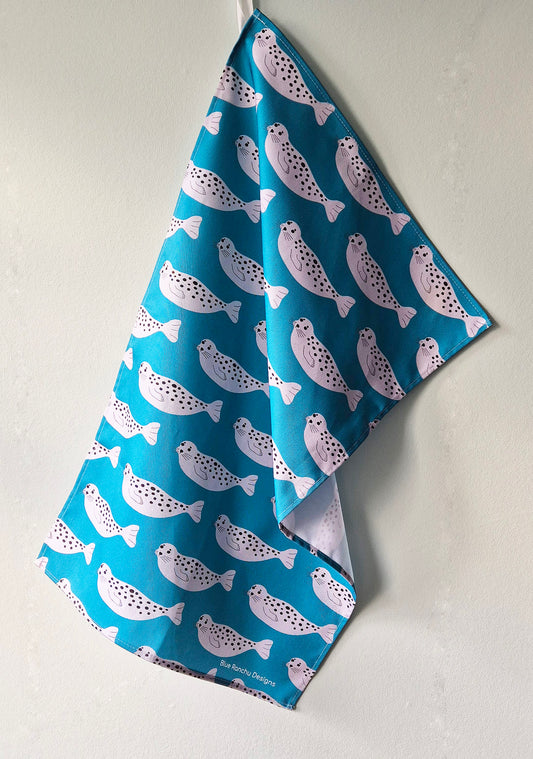Repeating Seal pattern on a turquoise background, cotton tea towel